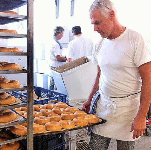 Bäcker betrachtet Backblech mit Bagels