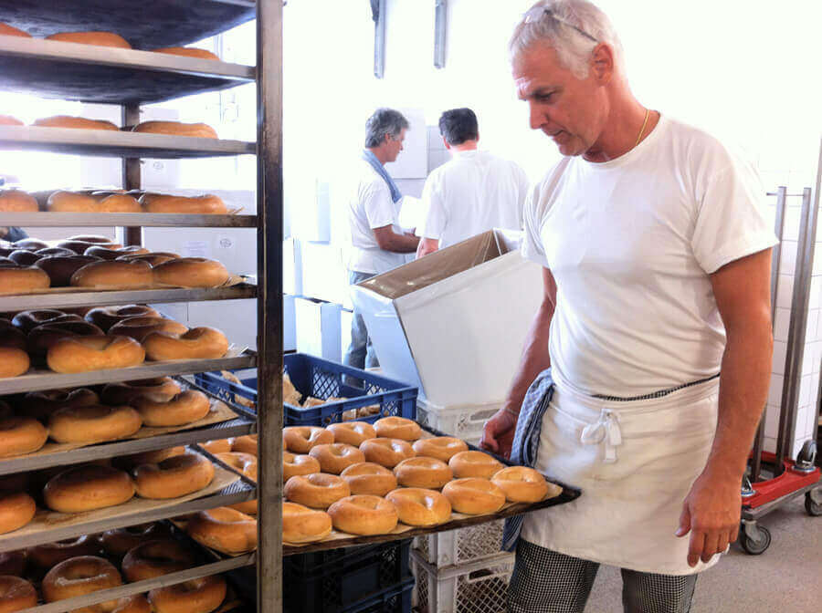 Baker looks at baking tray with bagels